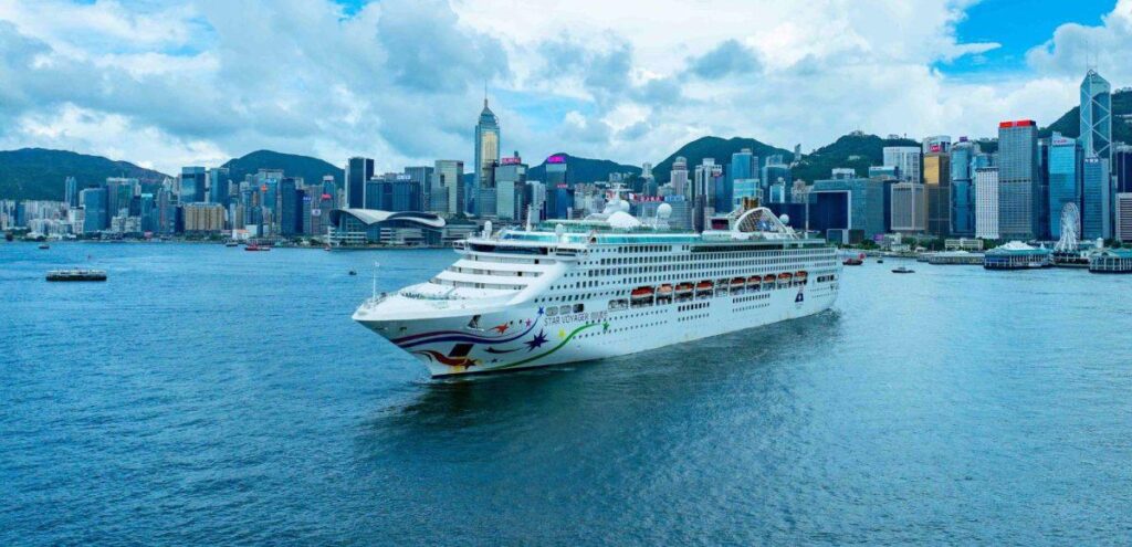 Cruise ship sailing in Victoria Harbour with the Hong Kong skyline behind