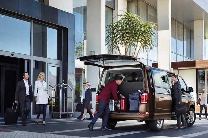 Chauffeur loading luggage into a van outside a hotel entrance