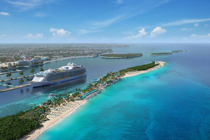 Aerial view of a cruise ship docked at a tropical island with white sand beaches