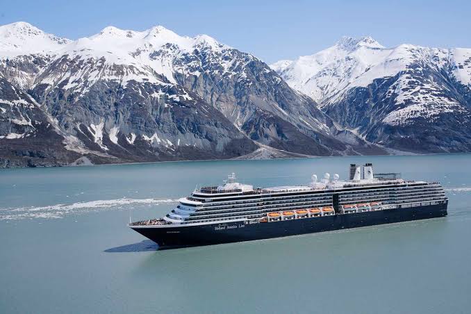 Holland America cruise ship sailing past snow-capped mountains in Alaska
