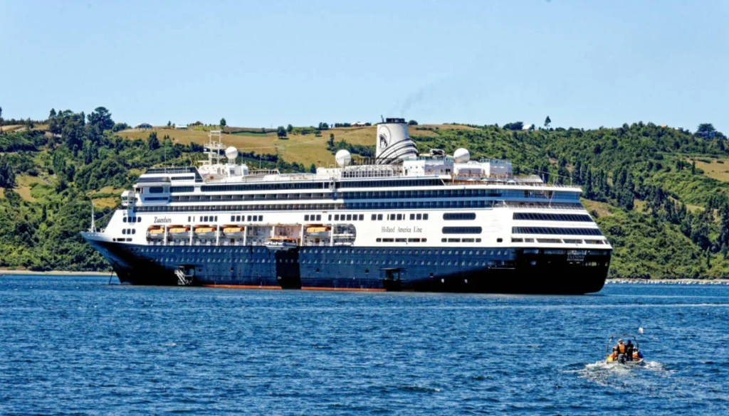 Holland America Zaandam cruise ship sailing near a green coastline
